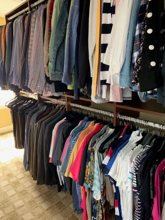 photo shows clothes hanging in a closet sorted by type